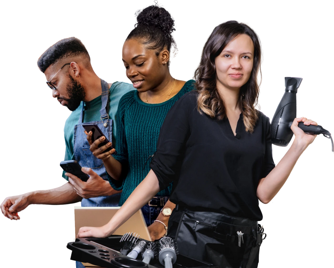 Three business owners standing together: one in an apron checking a phone, one working at a laptop, one holding a hairdryer beside a set of brushes